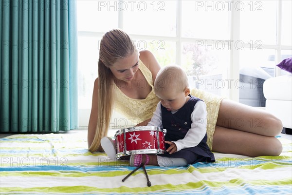 Young mother with daughter playing with drum. Photo : Mark de Leeuw