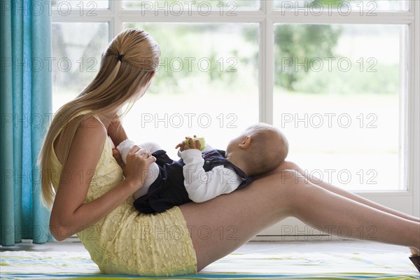 Young mother with daughter looking through window. Photo : Mark de Leeuw