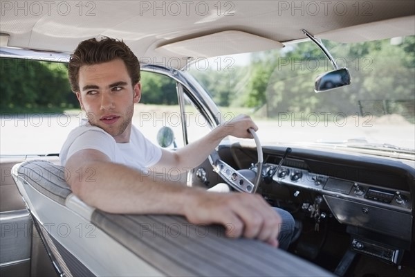 Young man in vintage car. Photo : Mark de Leeuw