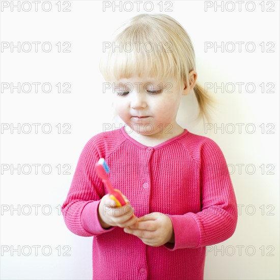 Studio shot of girl (2-3) holding toothbrush. Photo : Jessica Peterson