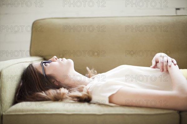 Young woman lying on sofa. Photo : Jessica Peterson