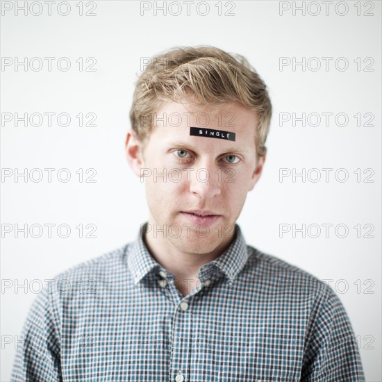 Studio shot of young man with word 'single' on forehead. Photo : Jessica Peterson