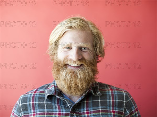 Portrait of smiling man with beard, studio shot. Photo: Jessica Peterson