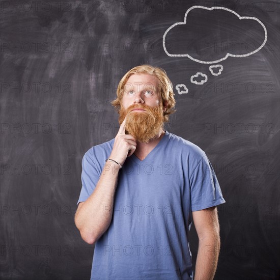 Man in front of blackboard with drawing depicting speech bubble. Photo : Jessica Peterson