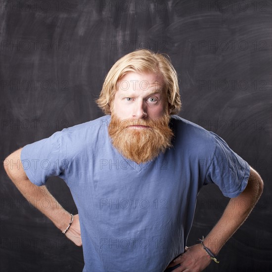 Man standing in front of blackboard staring at camera. Photo : Jessica Peterson