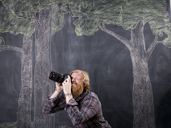 Man in front of blackboard taking pictures. Photo : Jessica Peterson