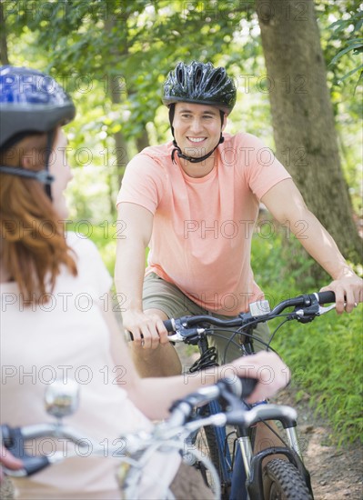 Couple cycling in forest. Photo: Tetra Images