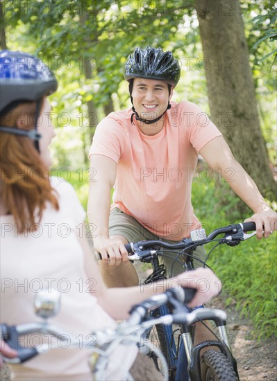 Couple cycling in forest. Photo : Tetra Images