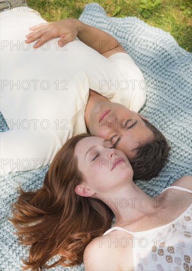 Portrait of couple lying on blanket. Photo : Tetra Images