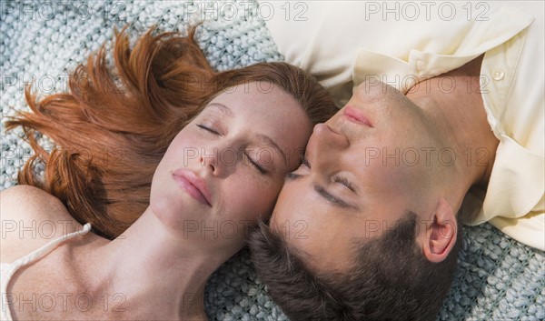Portrait of couple lying on blanket. Photo : Tetra Images