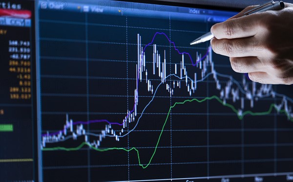 Hand pointing at financial graph, studio shot.