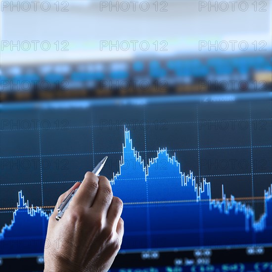 Hand pointing at financial graph, studio shot.