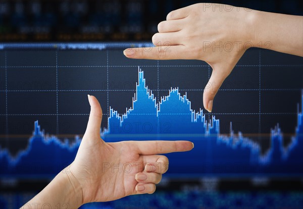 Hand pointing at financial graph, studio shot.