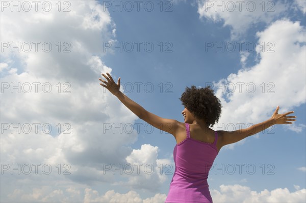 Woman stretching under blue sky.