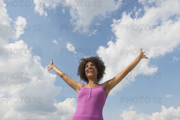 Woman stretching under blue sky.