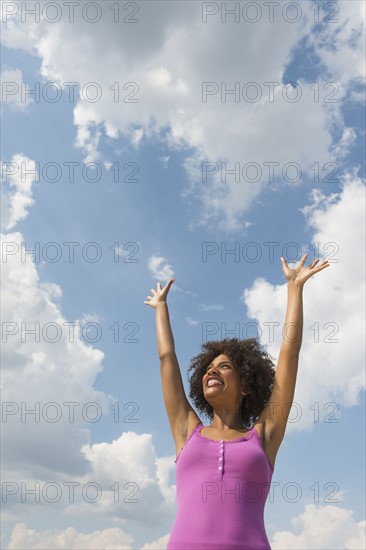 Woman stretching under blue sky.