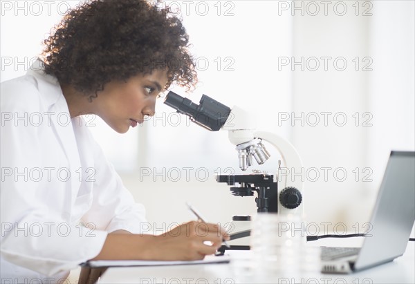 Woman using microscope in laboratory.