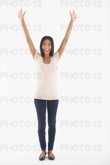 Portrait of woman with arms up, studio shot.