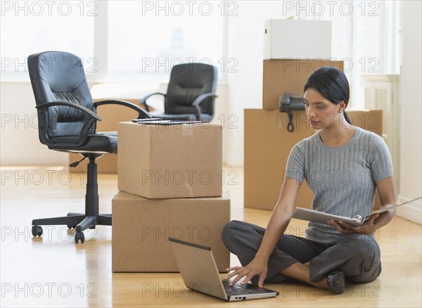 Businesswoman using laptop in new office.