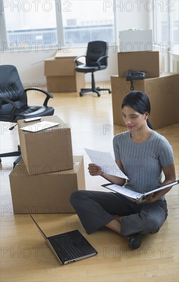 Businesswoman reading documents in new office.