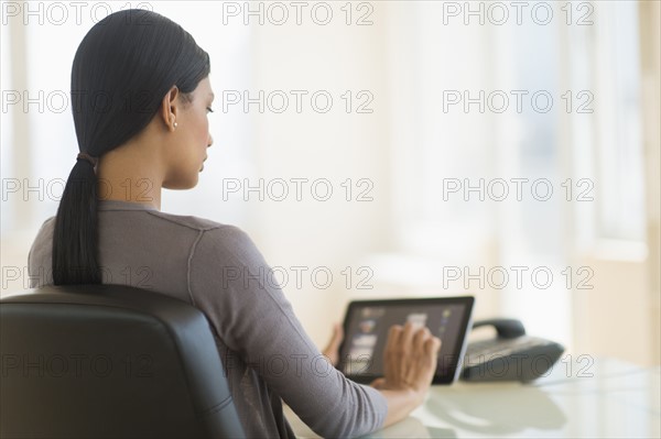 Businesswoman using digital tablet in office.