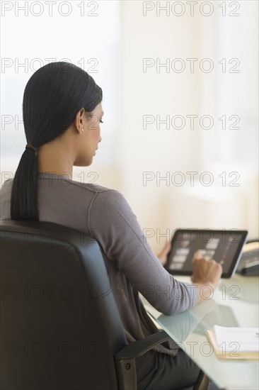 Businesswoman using digital tablet in office.