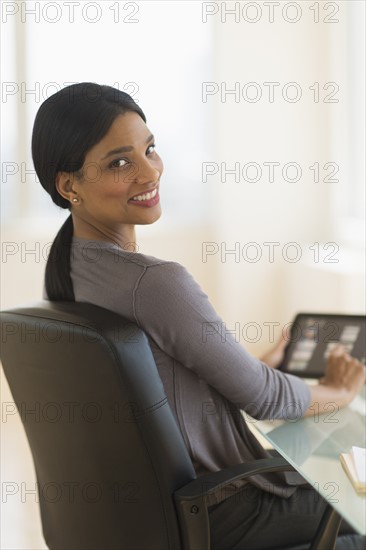 Businesswoman using digital tablet in office.