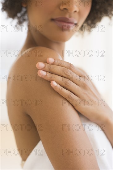 Beauty shot of woman touching shoulder, studio shot.