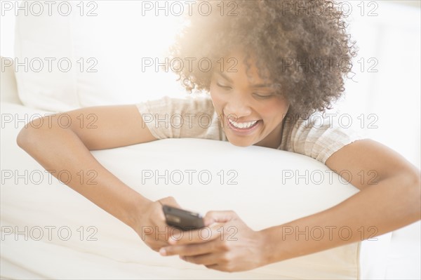 Woman relaxing on sofa using cell phone.