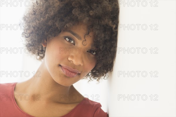 Portrait of woman leaning against wall, studio shot.