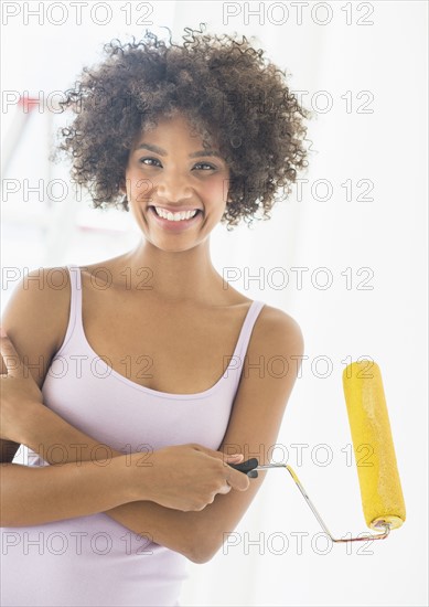 Portrait of woman holding paint roller.