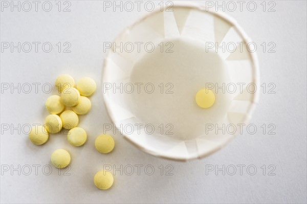 Yellow pills with cup, studio shot.