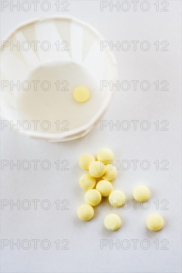 Yellow pills with cup, studio shot.