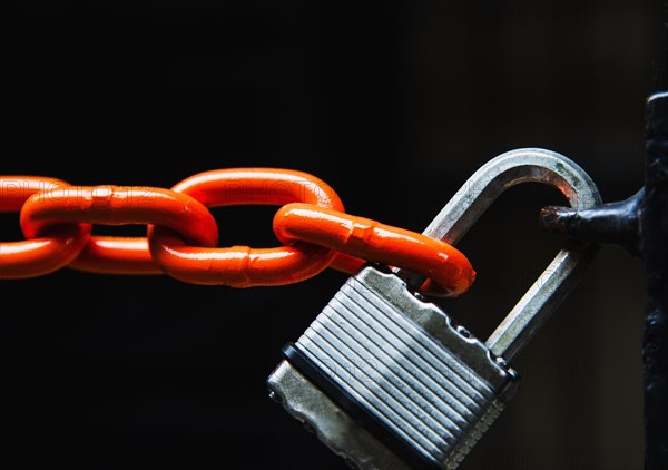 Chain with padlock on black background, studio shot.