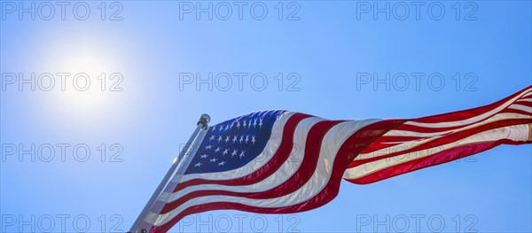 US flag against blue sky.