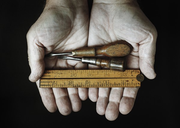 Studio shot of hands holding antique tools.