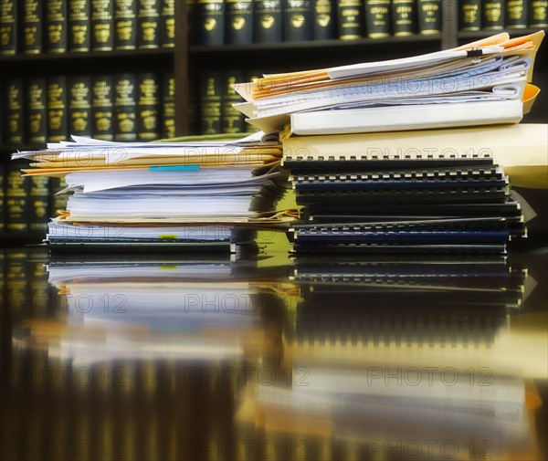 Stack of books and files on table.