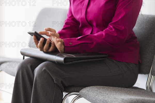 Woman sitting in waiting room and text messaging.