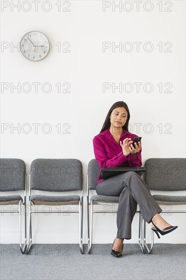 Woman sitting in waiting room and text messaging.