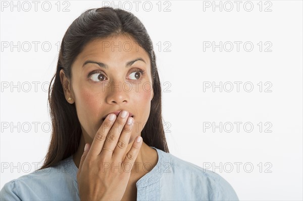 Studio shot of woman covering mouth with hand.