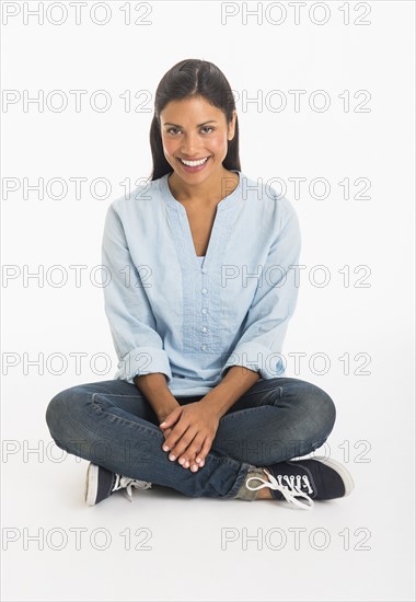 Studio shot woman sitting cross-legged.