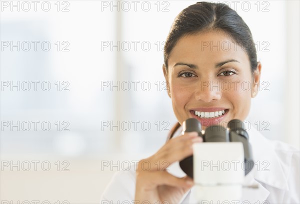 Female scientist looking through microscope.