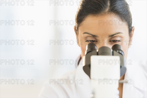 Female scientist looking through microscope.