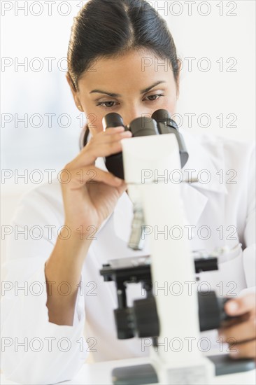 Female scientist looking through microscope.