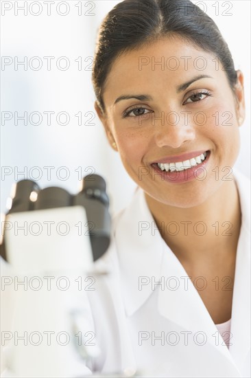 Female scientist looking through microscope.