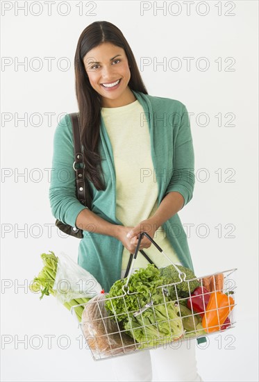 Studio shot of woman holding shopping basket with vegetables.