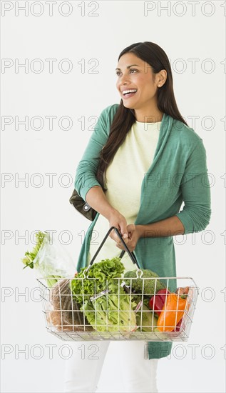 Studio shot of woman holding shopping basket with vegetables.