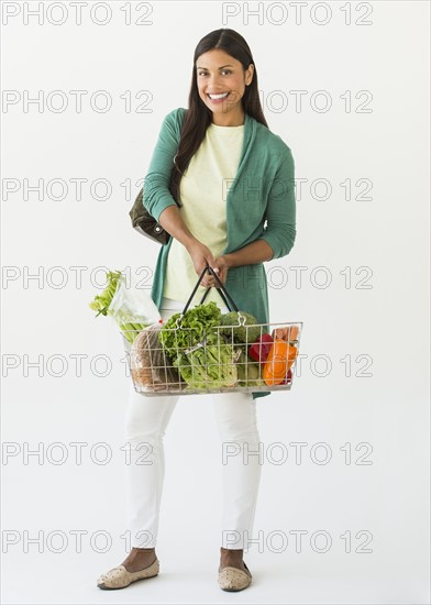 Studio shot of woman holding shopping basket with vegetables.