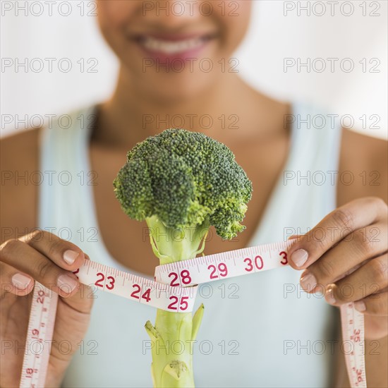 Woman measuring broccoli .