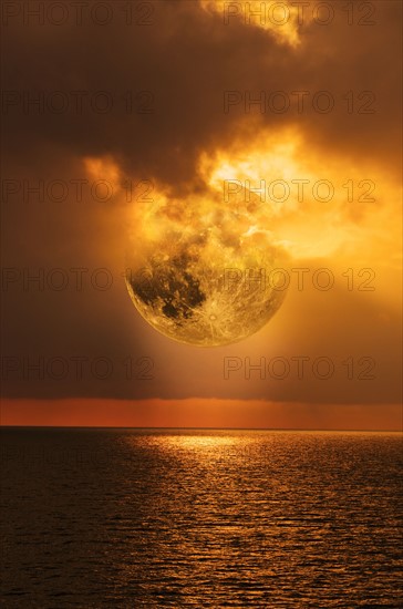 Moon and clouds at sunset over sea.